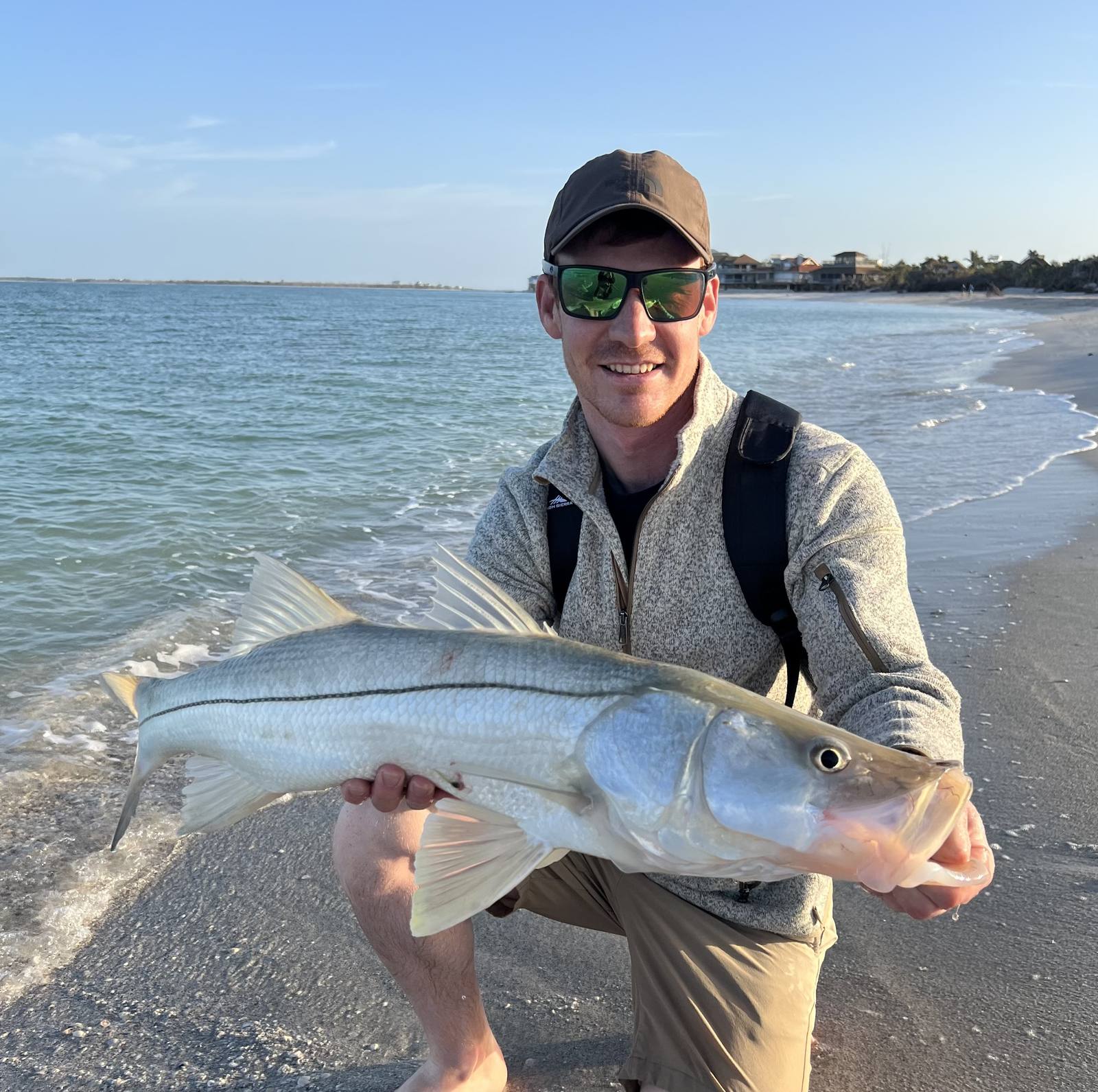A guest holding a large snook caught from the beach