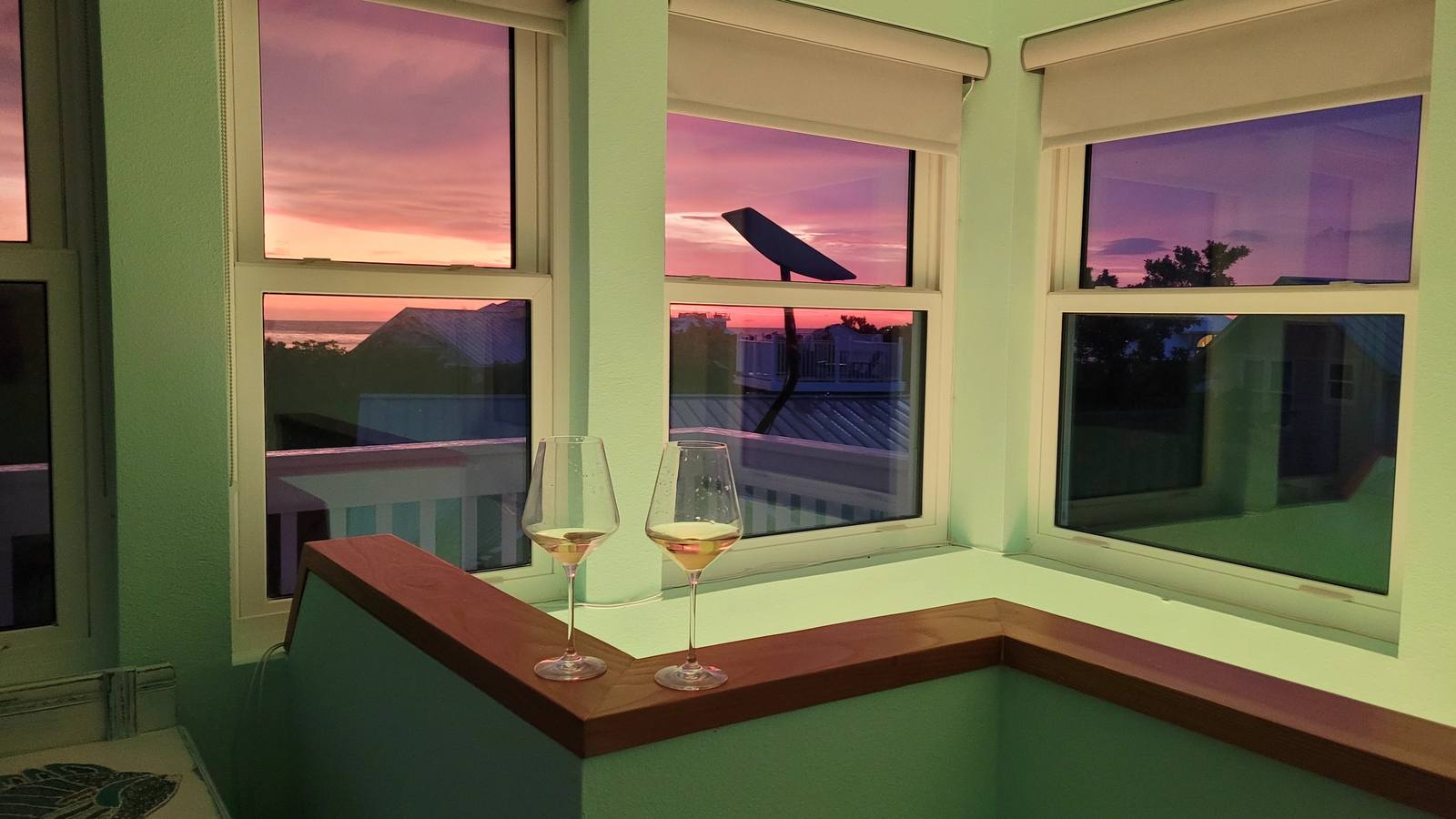 Sunset view from inside the observation room, wine glasses on the windowsill overlooking the rooftops