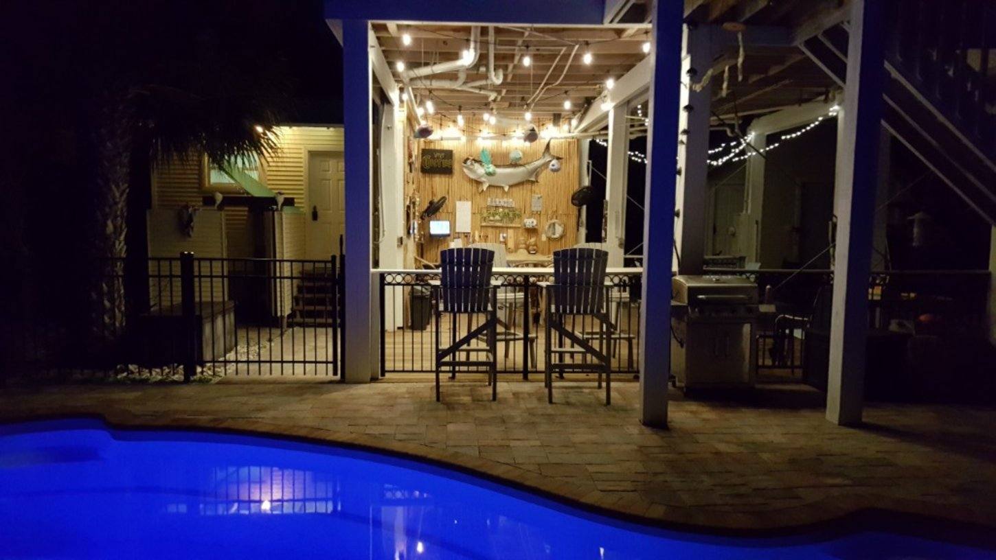 The Margaritaville-style pool bar lit up at night with string lights