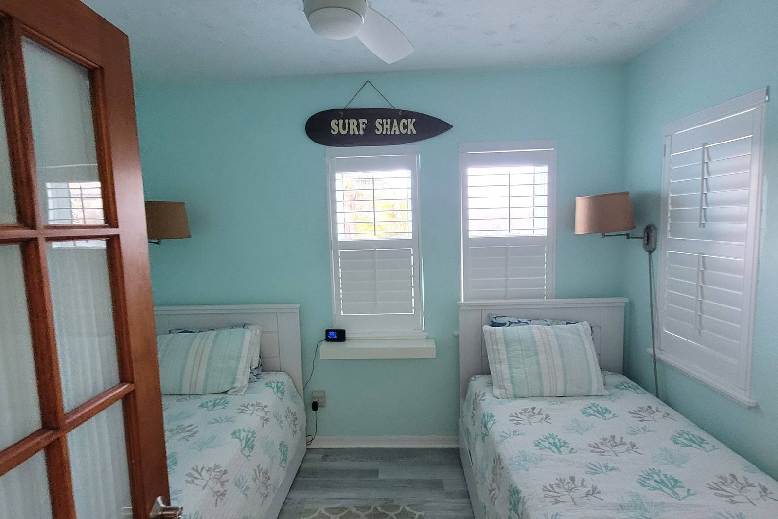 Twin bedroom with a Surf Shack sign and coral-patterned bedding